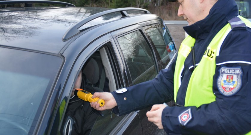 Zdjęcie policjanta trzymającego urządzenie do pomiaru alkoholu w wydychanym powietrzu/ podlaska.policja.gov.pl