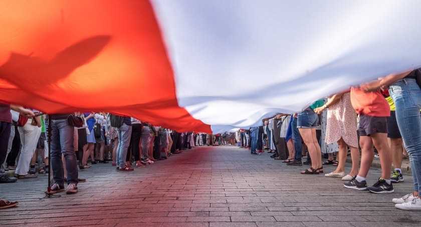 Zdjęcie ludzi trzymających polską flagę/ Pixabay.com