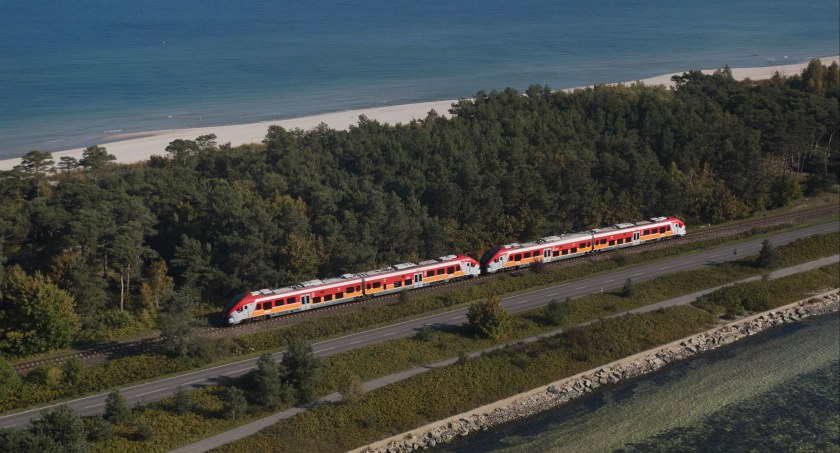 Zdjęcie pociągu jadącego po torach nad morzem/ Polregio