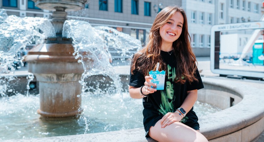 Zdjęcie młodej dziewczyny siedzącej z kubkiem lodów na fontannie w Białymstoku