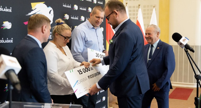 Zdjęcie z momentu wręczania symbolicznych czeków Wojciechowi Nowickiemu i jego trenerce przez przedstawicieli województwa podlaskiego/ podlaskie.eu