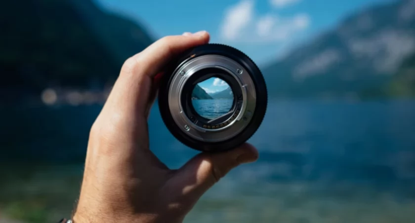 Zdjęcie obiektywu aparatu fotograficznego trzymanego w ręce/ PIK