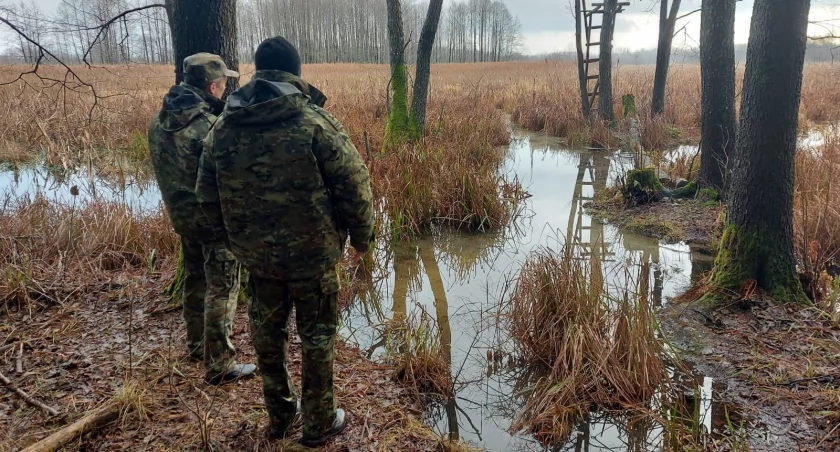 Zdjęcie strażników granicznych patrolujących teren przy samochodzie służbowym/ SG