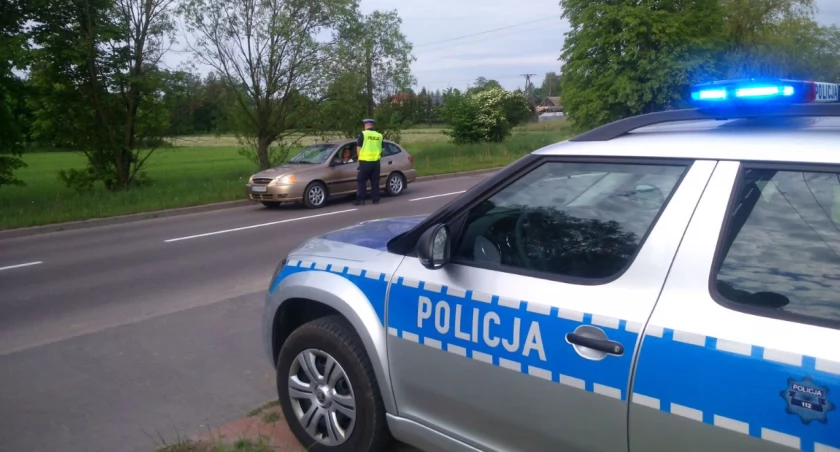 Zdjęcie radiowozu i policjanta kontrolującego kierowcę/ podlaska.policja.gov.pl
