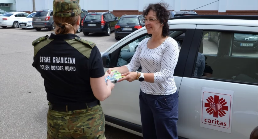 Zdjęcie strażniczki granicznej odbierającej pomoc od przedstawicieli Caritas Archidiecezji Białostockiej/ SG