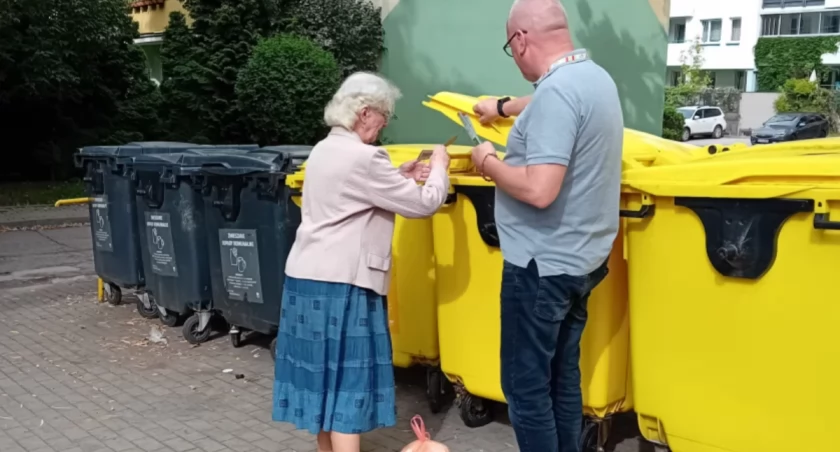 Zdjęcie mężczyzny rozdającego broszurę przy kubłach ze śmieciami/ bialystok.pl
