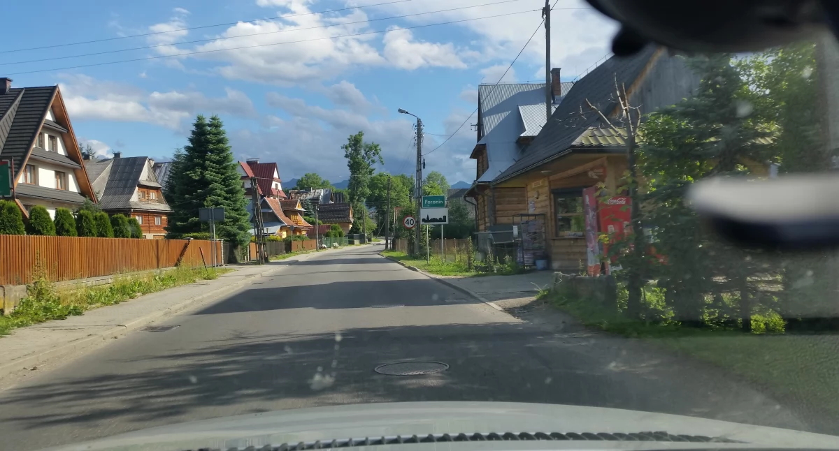 Zdjęcie znaku miejscowości w górach i zabudowy góralskiej/ DDB