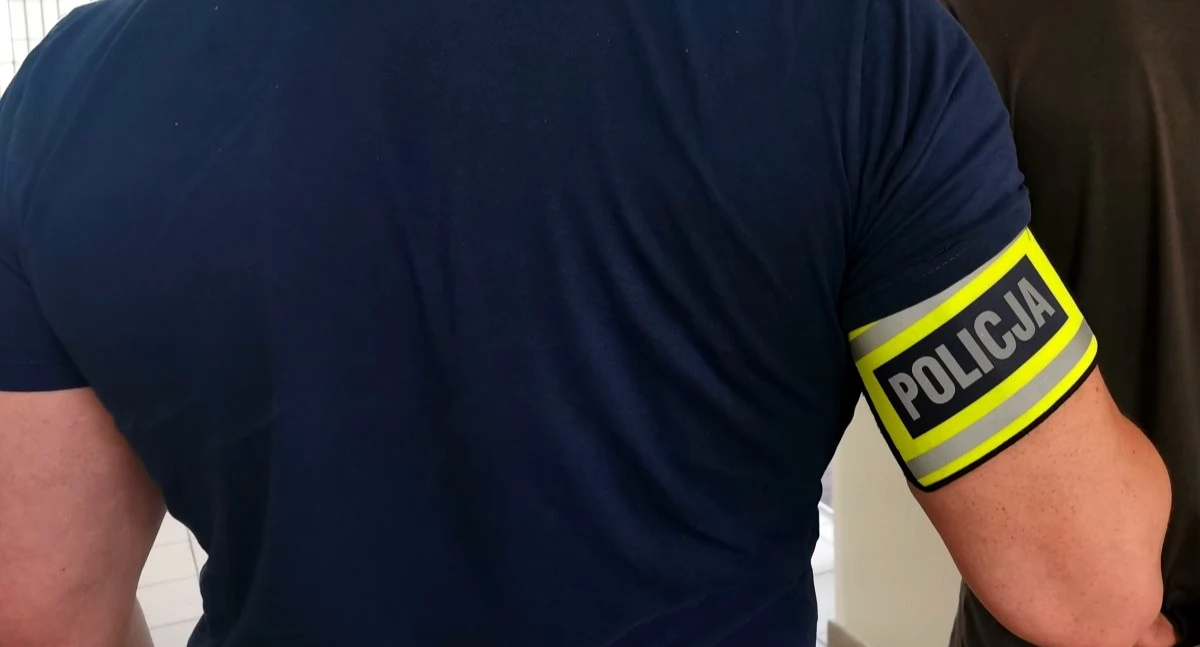 Zdjęcie zatrzymanego mężczyzny w kajdankach prowadzonego przez policjanta/ podlaska.policja.gov.pl