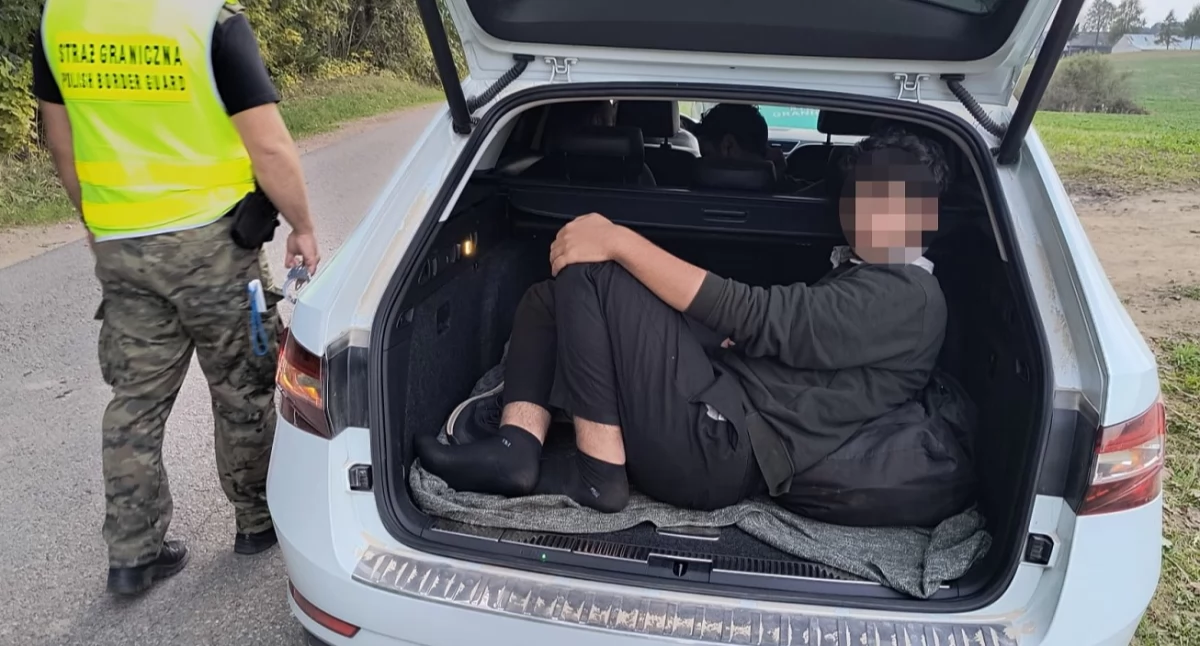 Zdjęcie strażnika granicznego przy samochodzie, którym przewożeni byli nielegalni migranci/ SG