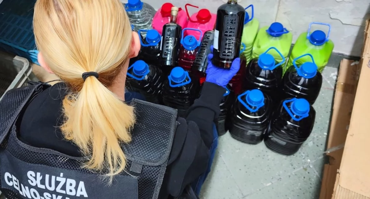 Zdjęcie funkcjonariuszki KAS przy zarekwirowanym alkoholu/ KAS