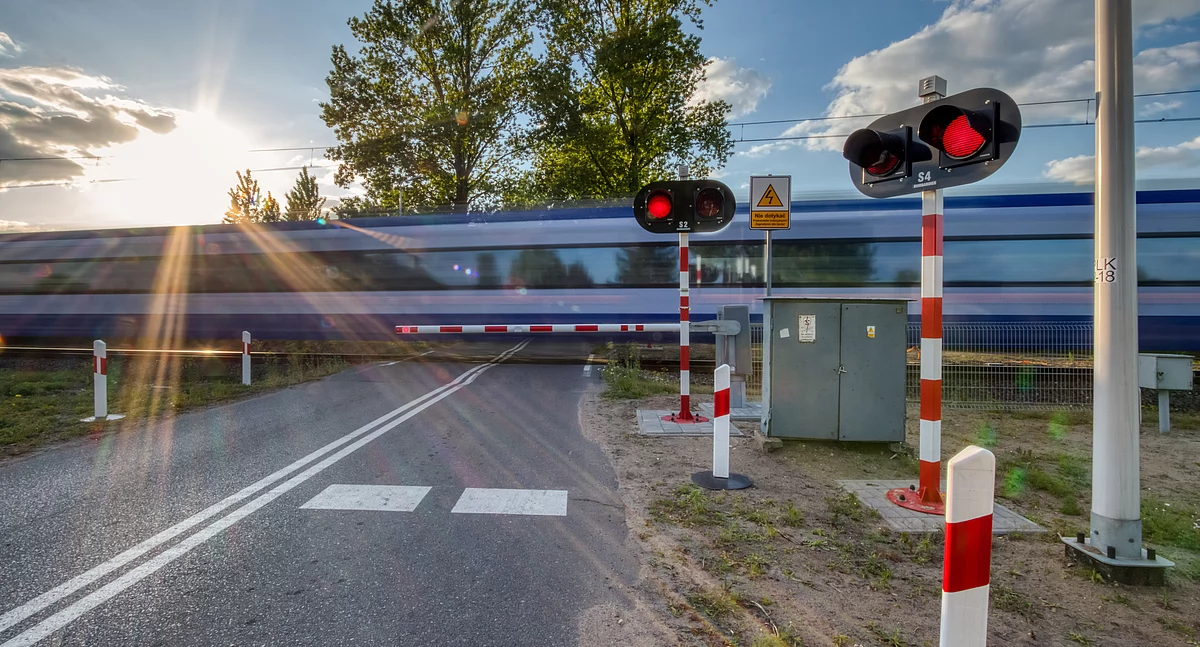 Zdjęcie przejazdu kolejowego z przejeżdżającym pociągiem/ PKP PLK