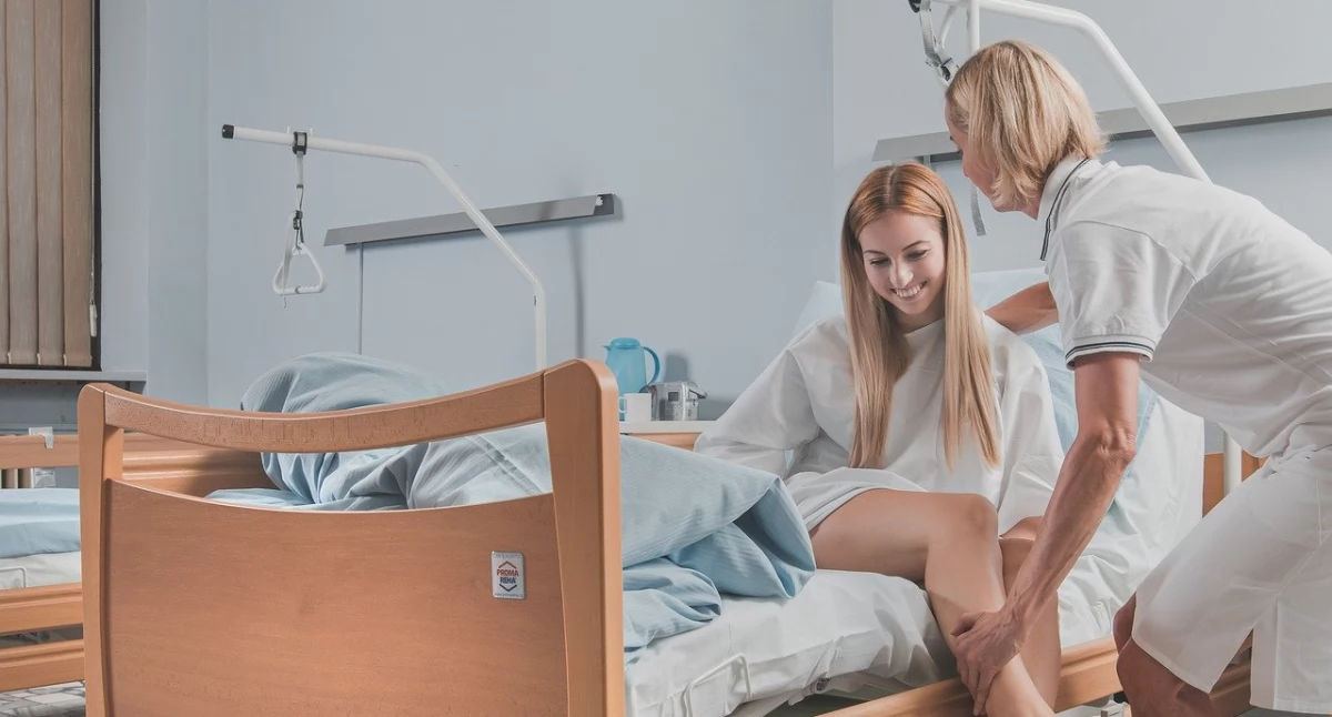 Zdjęcie kobiety na łóżku rehabilitacyjnym i pielęgniarki/ Pixabay.com