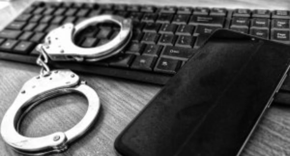 Zdjęcie kajdanek i telefonu na klawiaturze/ podlaska.policja.gov.pl