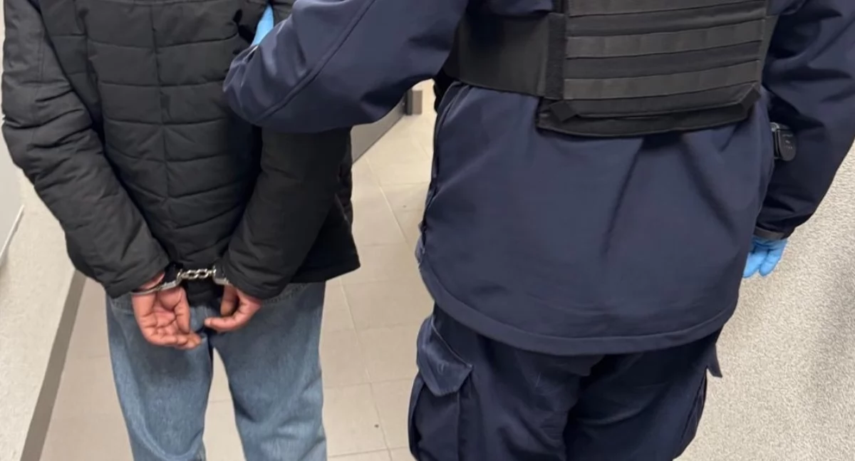 Zdjęcie zatrzymanego mężczyzny prowadzonego przez policjanta/ podlaska.policja.gov.pl