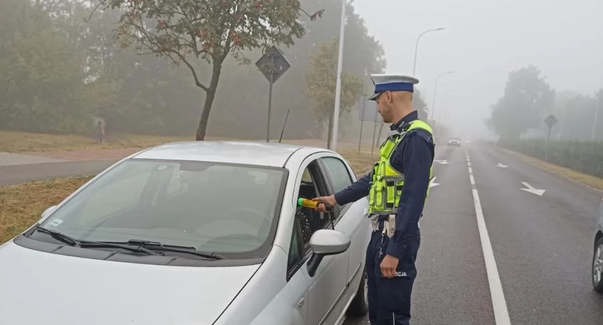 Zdjęcie policjanta kontrolującego trzeźwość kierowcy/ podlaska.policja.gov.pl