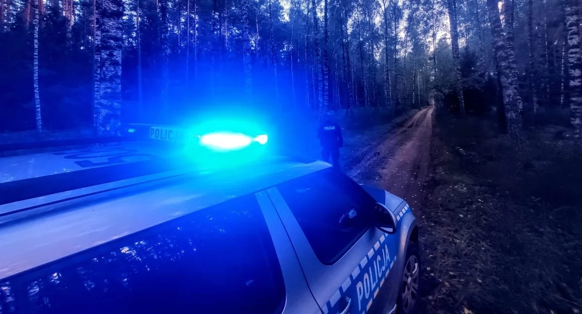 Zdjęcie policjanta przy radiowozie w lesie/ podlaska.policja.gov.pl