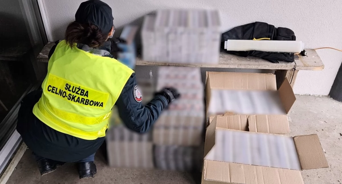 Zdjęcie funkcjonariuszki KAS przy zarekwirowanych nielegalnych papierosach/ KAS