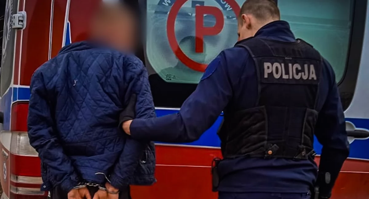Zdjęcie policjanta z zatrzymanym mężczyzną przy karetce pogotowia/ podlaska.policja.gov.pl