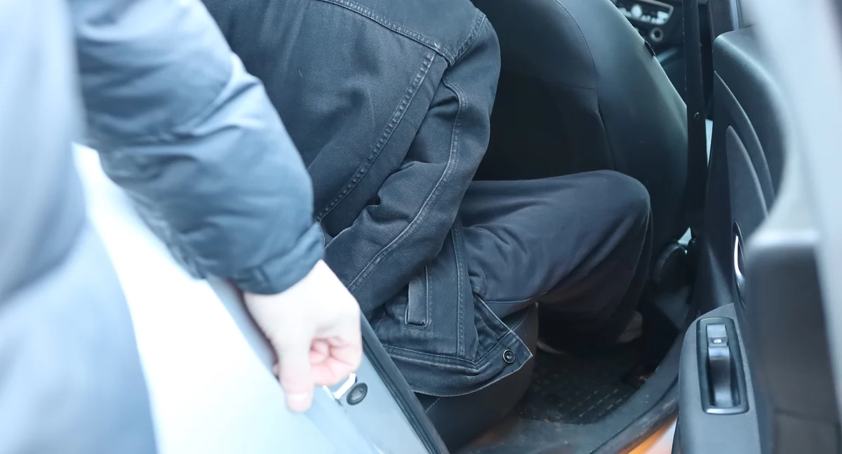 Zdjęcie zatrzymanego mężczyzny w samochodzie w kajdankach/ podlaska.policja.gov.pl
